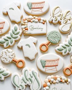 many decorated cookies are displayed on a white surface with the word baby spelled in green and orange