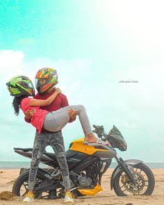 a man and woman sitting on top of a motorcycle in the sand at the beach