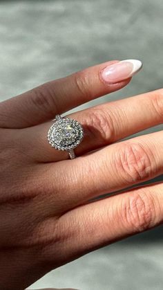 a woman's hand with a diamond ring on her finger and white nail polish