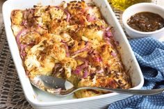 a casserole dish with onions and sauce on the side