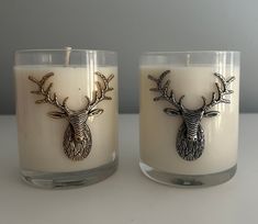 two candles with deer heads on them sitting next to each other