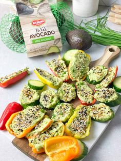 peppers stuffed with avocado are on a cutting board next to other vegetables and spices