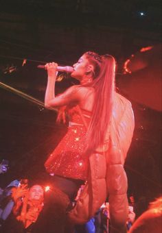 a woman standing on top of a stage holding a microphone in her hand and singing