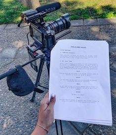 a person holding a piece of paper in front of a camera on a tripod