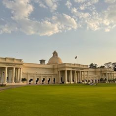 a large building with columns and a clock on it's face in the middle of a grassy area