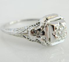 an antique style diamond ring with filigree accents