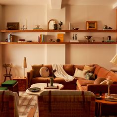 a living room filled with lots of furniture next to a wall mounted book shelf covered in books