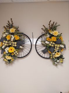 two bicycle wheels decorated with yellow and white flowers are hanging on the wall next to each other