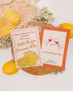 two wedding stationery cards on a wooden plate with lemons