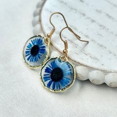 "This listing is for one pair of Cobalt Blue tiny, gold or silver rimmed , Needle Chrysanthemum resin earrings. These Needle Chrysanthemum resin earrings are light weight, hand poured, carefully crafted and uniquely designed! Created with real dried flowers, these earrings are a perfect gift for a friend, girlfriend, wife, fiancé or even for yourself!   -These earrings say \"Fun\"!  Wear these the next time you go out, or on your favorite family event.  All of our earrings use NICKEL FREE AND LEAD FREE HYPOALLERGENIC HOOKS.   Every earring is hand crafted and so each are unique! CHECK OUT OTHER BEAUTIFUL OPTIONS FROM OUR FUN CHRYSANTHEMUM COLLECTION -Dandelion Tiny Round Needle Chrysanthemum Earrings: https://www.etsy.com/listing/1517988191 -Ocean Blue Tiny Round Needle Chrysanthemum Earri Gold Teardrop Birth Flower Earrings, Metal Flower Earrings Gift Round Shape, Blue Teardrop Flower Earrings Nickel Free, Blue Teardrop Nickel Free Flower Earrings, Blue Teardrop Nickel-free Flower Earrings, Gift Metal Flower Earrings, Blue Drop Earrings As Gift For Her, Blue Birth Flower Earrings, Blue Round Flower Earrings With Ear Wire