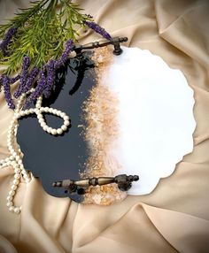 an arrangement of pearls, beads and flowers on a black surface with a white plate