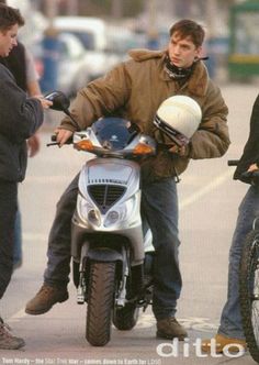 a man on a motorcycle talking to two men standing next to him and another person sitting on the bike