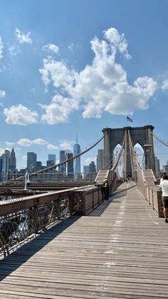 people walking across the brooklyn bridge on a sunny day