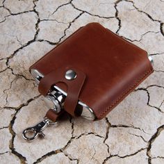 a brown leather wallet with a keychain attached to it on a cracked surface