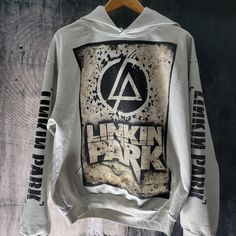 a white hoodie with the words linkin park printed on it, hanging on a wooden hanger