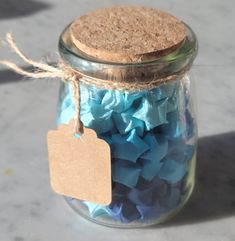 a jar filled with lots of blue and purple confetti next to a tag