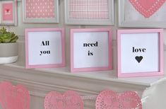 pink and white frames with hearts hanging on the wall next to a potted plant