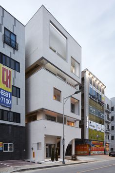 the building is white and has many windows on each side, along with other buildings