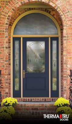 a blue front door with glass and iron grills on the side of a brick building