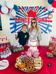 a woman standing next to a boy in front of a table with donuts and pretzels