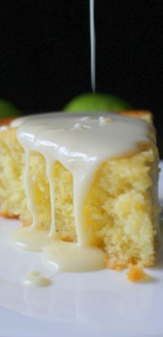 a piece of cake with icing on a white plate next to some green apples