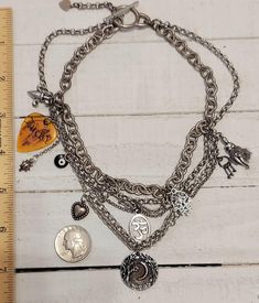 This is a Vintage Six intertwined  Strand of Stainless Steel Mixed size Multi Chain Choker Necklace with various Whimsical Charms- Known lovingly as a NECKMESS ; a LUCKY guitar pick, ladybug, black evil eye, heart, Om, Hamsa, keys on a tiny ring, lady with Chain link movable skirt and the bottom drop Charm is round with a Crescent Moon surrounded by trees.  This special Necklace is a more Oxidized Silver and a Toggle Clasp.  This is a truly unique and one of a Kind design.  *PLEASE NOTE DO NOT SUBMERGE YOUR JEWELRY IN WATER OR WEAR WHILE SLEEPING * Cheap Trendy Multi-strand Charm Necklaces, Trendy Multi-strand Metal Charm Necklaces, Silver Layered Multi-strand Charm Necklaces, Silver Multi-strand Layered Charm Necklaces, Adjustable Silver Multi-strand Charm Necklaces, Charm Necklace Diy, Recycled Necklaces, Tiny Rings, Special Necklace