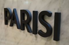 the word paris is spelled in black letters on a marble wall with dark metal lettering