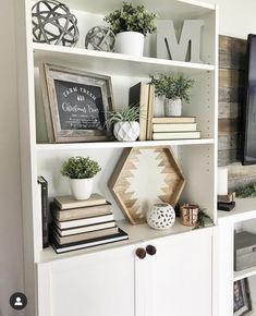 a white bookcase with books and plants on it, along with an entertainment center