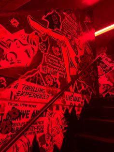 the stairs are covered with graffiti and stickers in red light, while black background is lit up