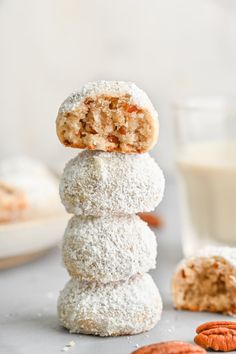 three donuts stacked on top of each other next to a glass of milk and some pecans