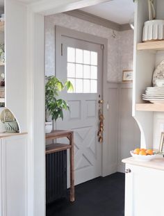 an open door leading to a kitchen with white walls and black flooring on the other side