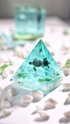 there is a small glass pyramid on the table with rocks and water in front of it