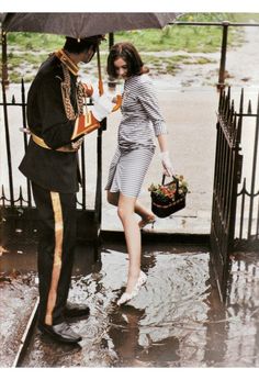 a man and woman are standing in the rain under an umbrella, one holding a flower pot