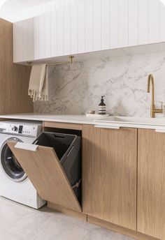 an open dishwasher in a kitchen next to a sink and counter top with marble