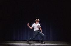 a man in white shirt and black pants on stage