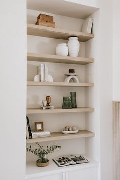 the shelves are filled with books, vases and other decorative items in white room