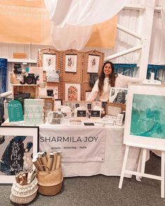 a woman standing behind a table with pictures on it