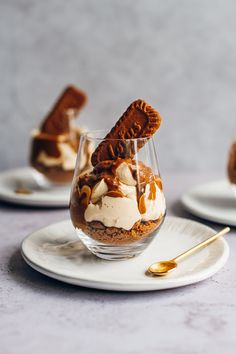 two desserts on white plates with gold spoons and silverware in the background