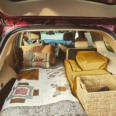 the back end of a car with its trunk open and pillows on it's bed