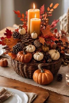 a basket filled with pumpkins, pine cones and candles on top of a table