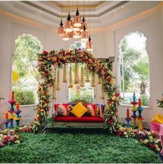 a room decorated in bright colors with flowers and greenery on the floor, including a red couch