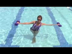 a woman is in the water with two purple dumbs on her arms and legs