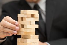 a man in a suit is stacking wooden blocks with one hand and the other