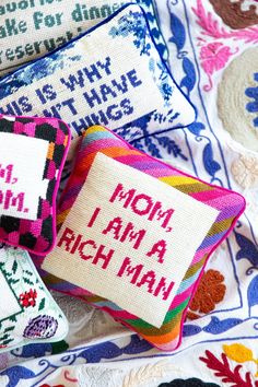 cross stitched pillows with words on them sitting next to each other in different colors