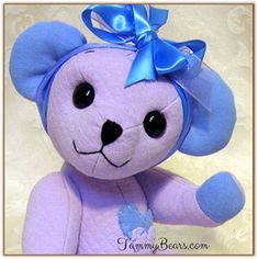 a purple teddy bear with a blue bow on it's head