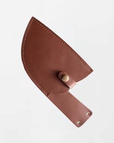 a brown leather belt hanging from the side of a white wall with a button on it