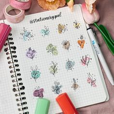 an open notebook with stickers and markers on it next to some flowers, pencils and pens