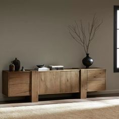 a large wooden cabinet with two vases on it's sides and a window in the background