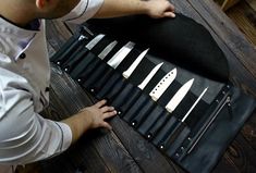 a man sitting at a table with several knives in a case on top of it