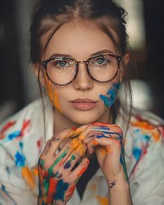 a woman with glasses and paint all over her face is posing for the camera,